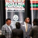 people standing at front of room before vertical banner, Black Boys and Men National Symposium